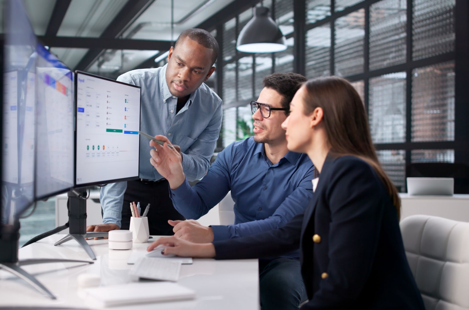 Colleagues in a modern office review analytics on a large monitor together