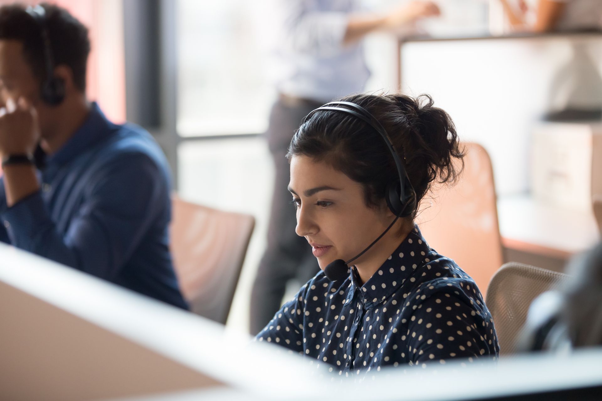 Woman wearing headphones working at a desk in an office setting