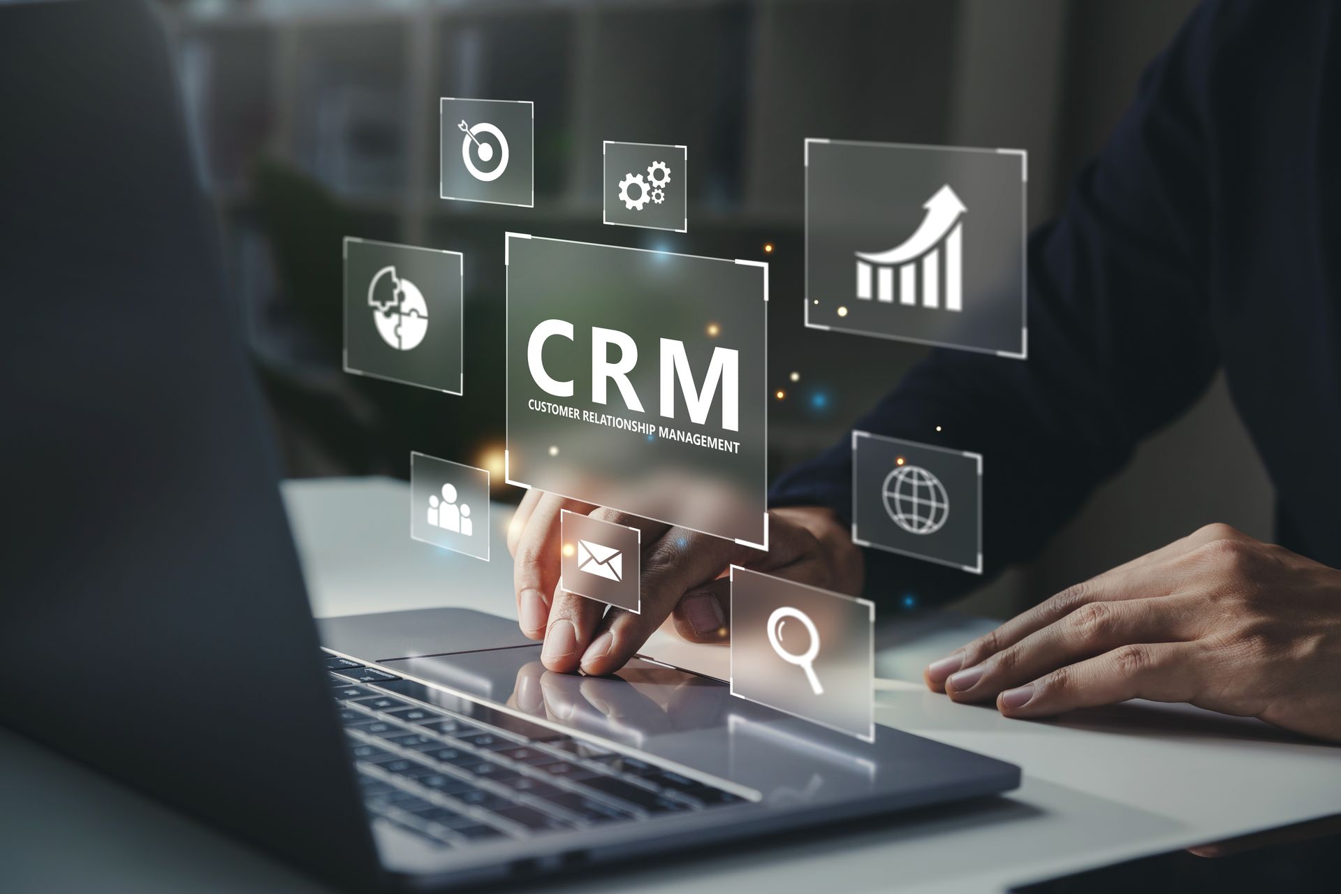 Hands typing on a laptop with floating CRM, analytics, and search icons overlayed