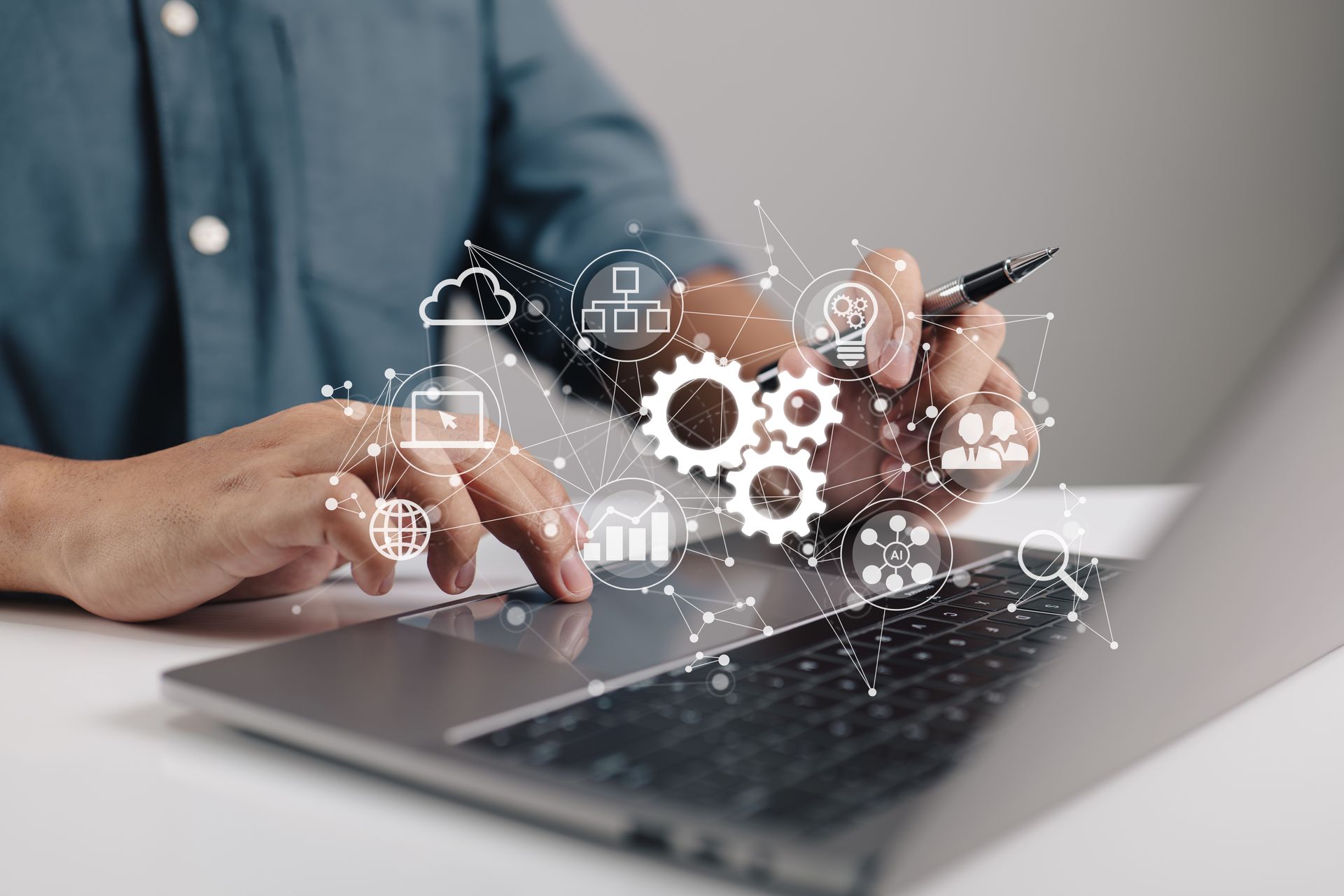 Person using a laptop with digital gear and cloud icons overlaying the screen