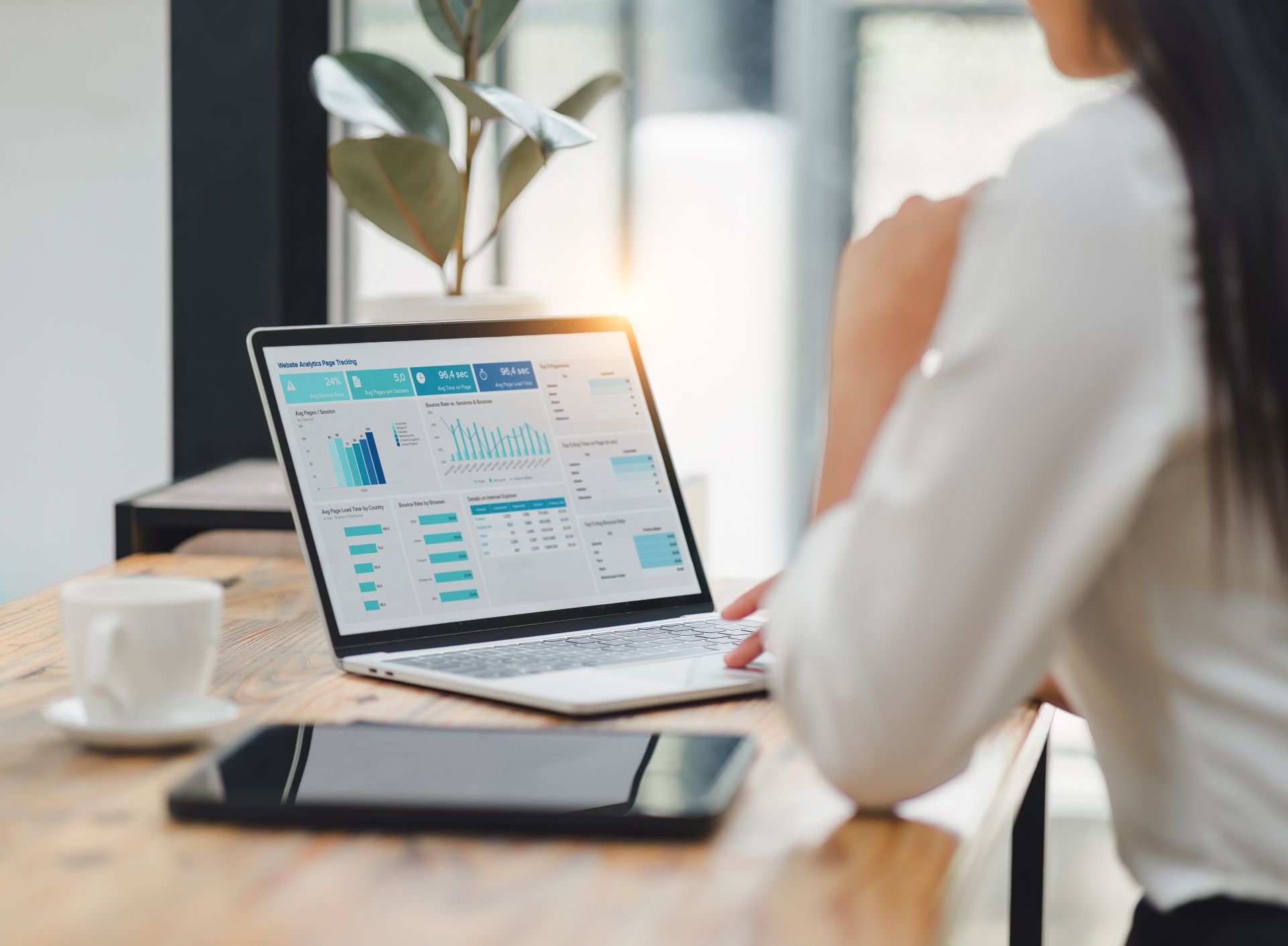 Woman working on a laptop with analytics charts at a desk