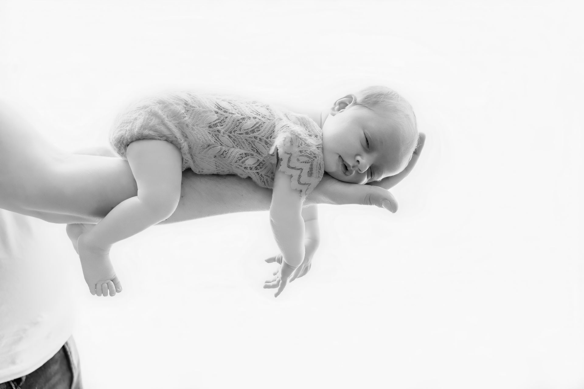 Slapende baby liggend op de arm van een volwassene, zwart-wit