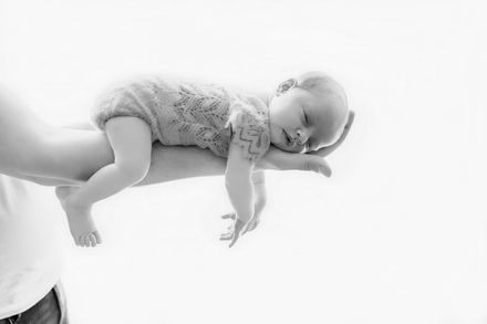 Slapende baby liggend op de arm van een volwassene, zwart-wit