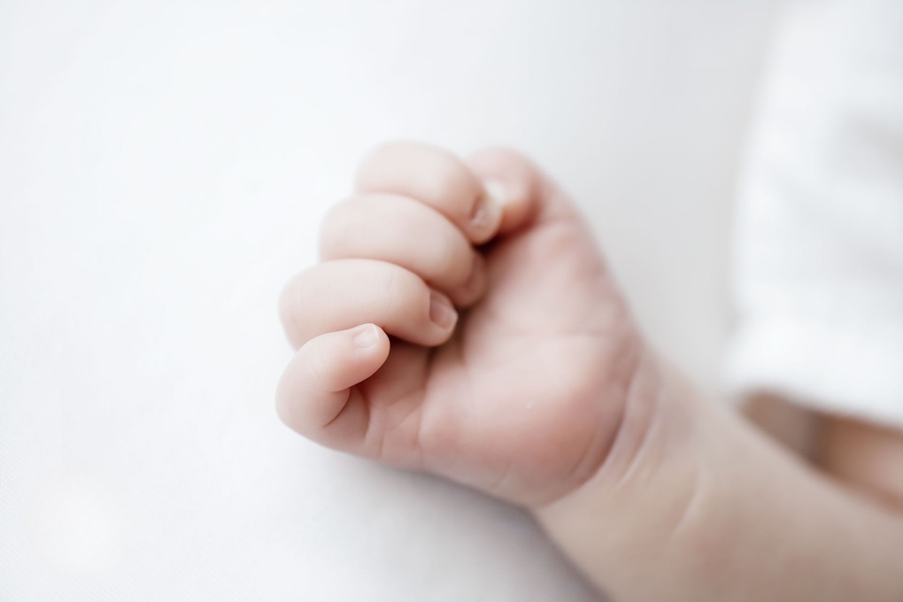 Klein, gebald babyhandje op een witte achtergrond