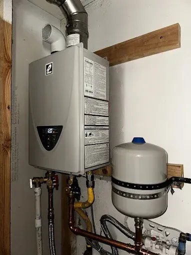 Wall-mounted boiler and water tank with pipes in a utility room