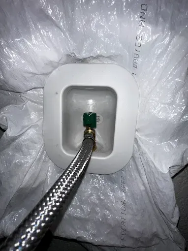 Braided hose connected to a green fitting inside a white plastic housing amid clear packing material