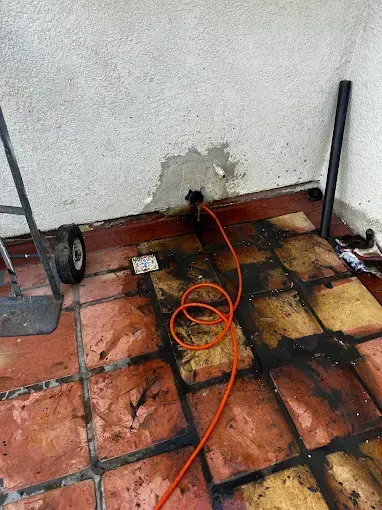 Damaged wall outlet with exposed wiring on a tiled patio floor