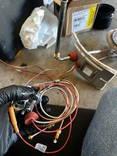 Coiled copper tubing and wires beside a metal appliance and tools on a concrete floor