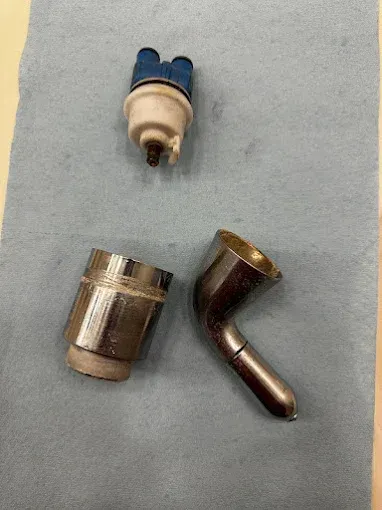 Three small metal and plastic pipe fittings on a light blue cloth background