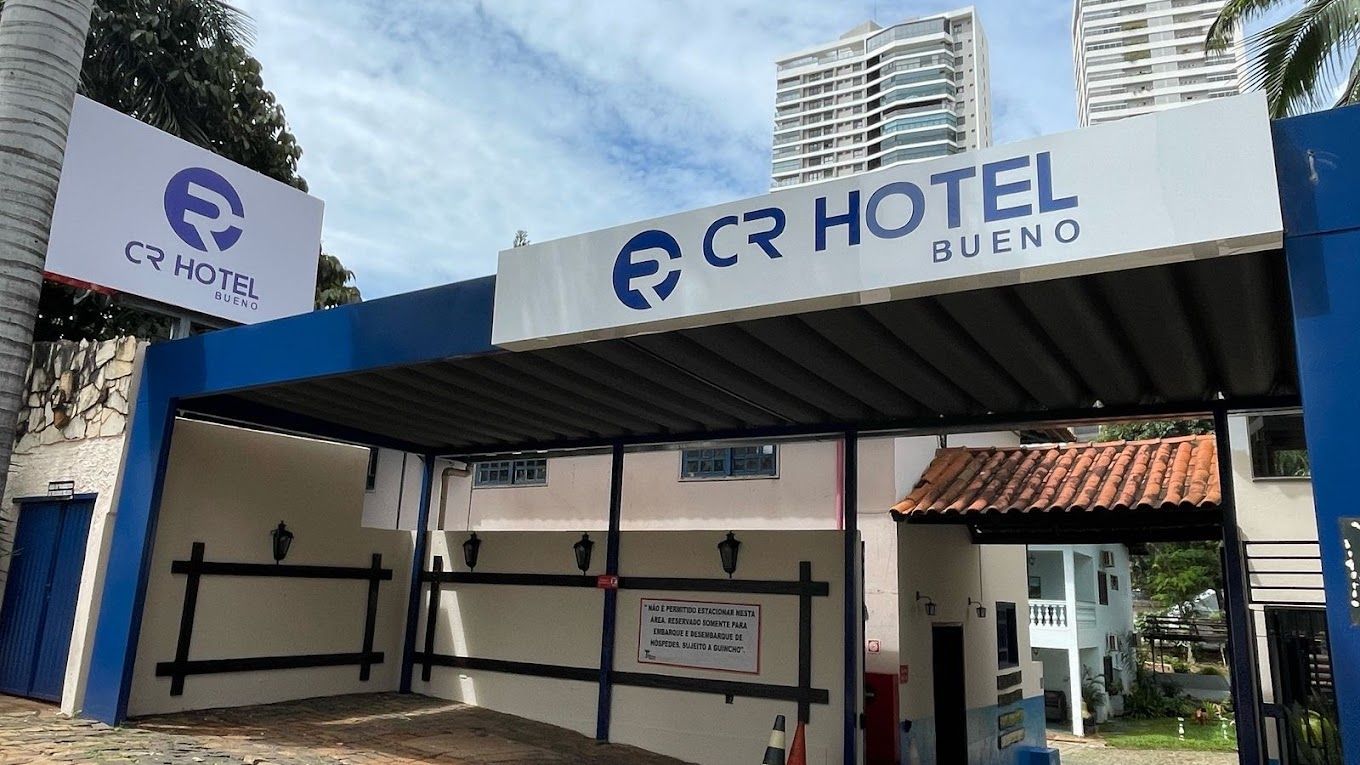 Um prédio branco e azul com uma placa que diz 'Cr hotel bueno' CR HOTEL BUENO
