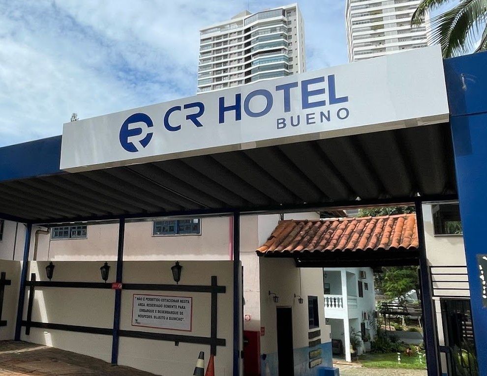 Um prédio branco com uma placa azul que diz cr hotel bueno CR HOTEL BUENO