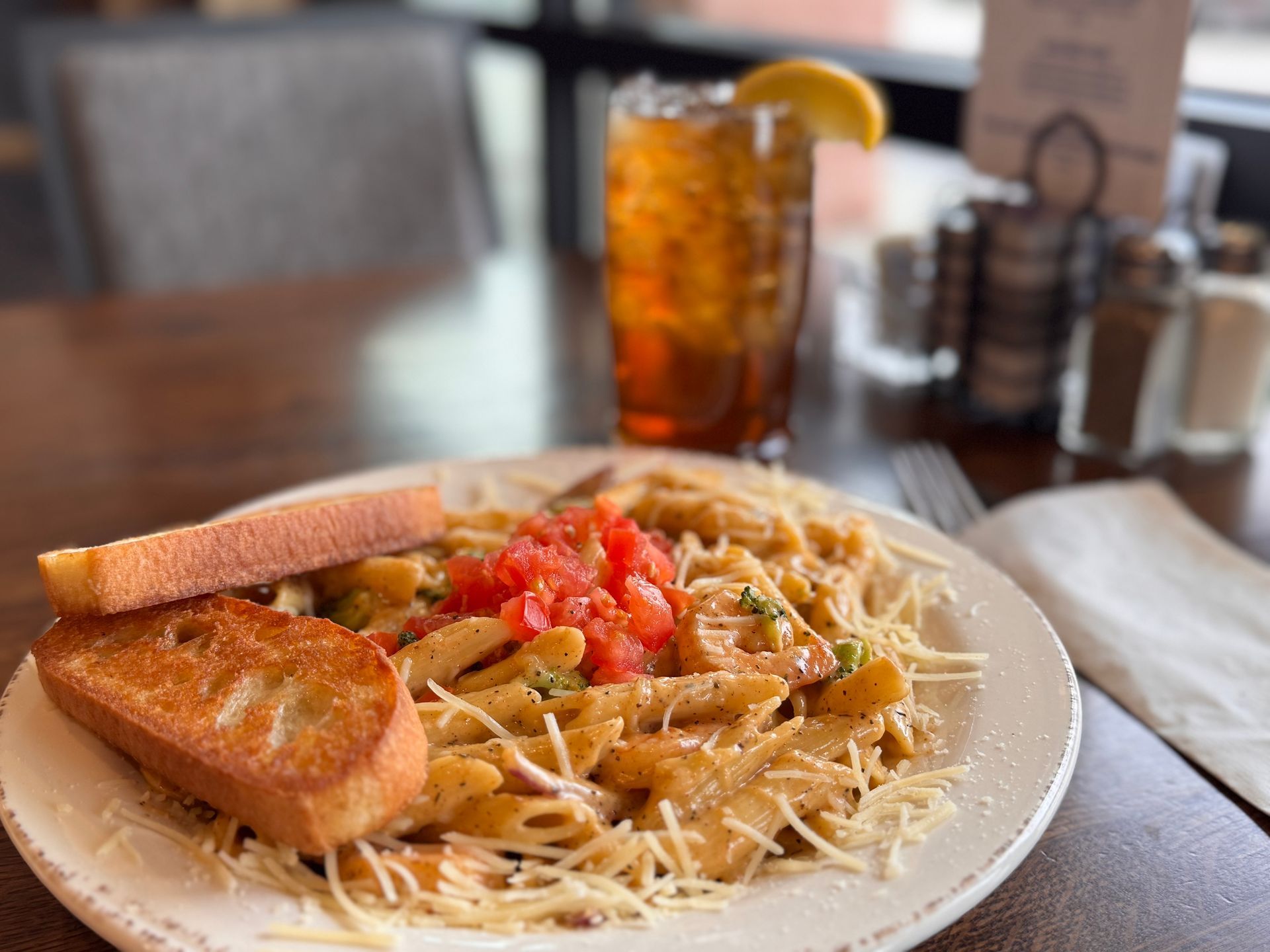 Pasta dish with tomatoes and garlic bread, iced tea with lemon.