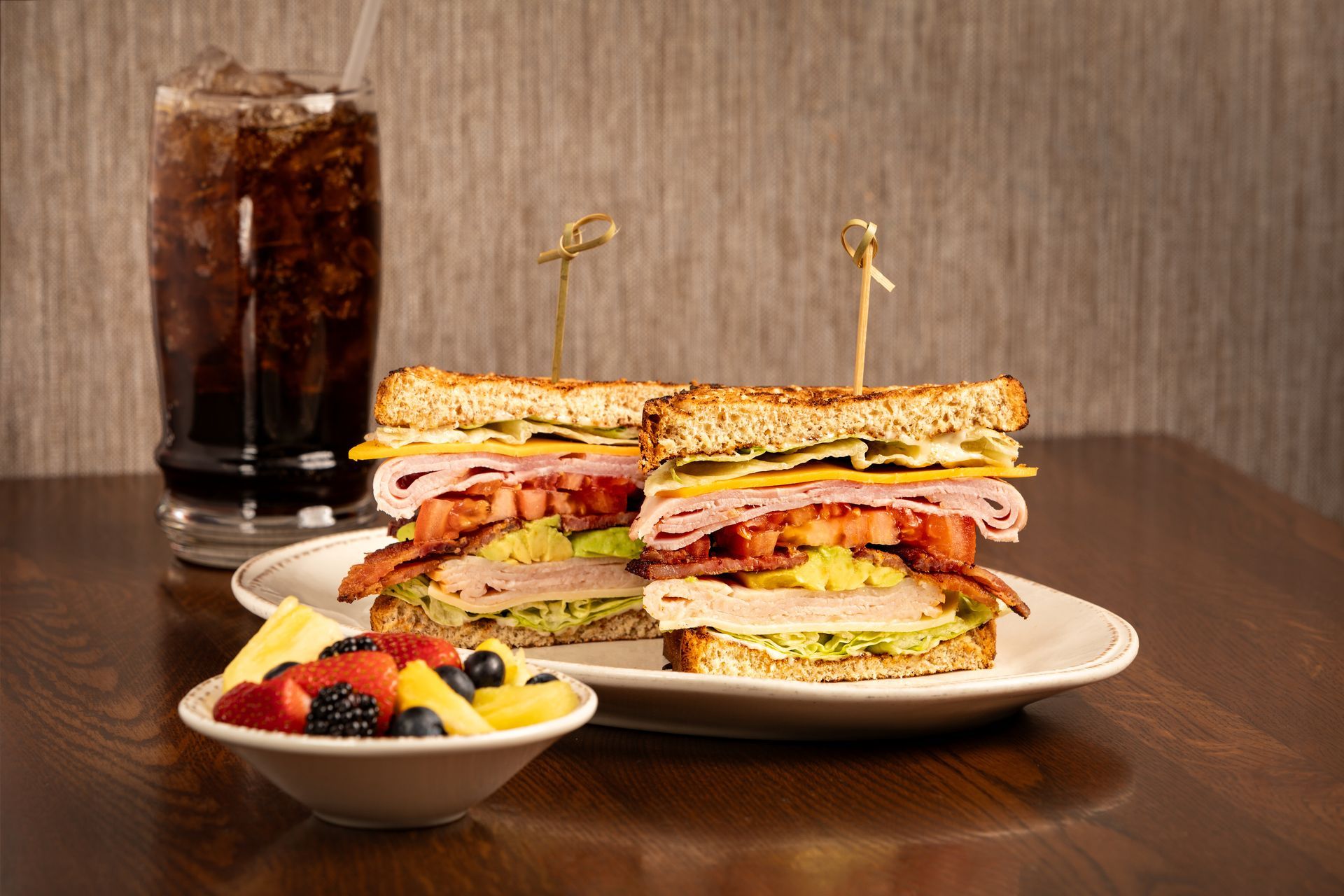 Sandwich with fruit and soda on a plate.