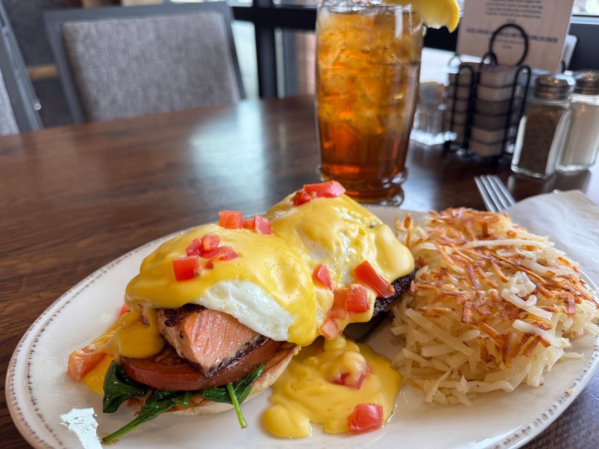 Eggs Benedict with salmon, hash browns, and iced tea.