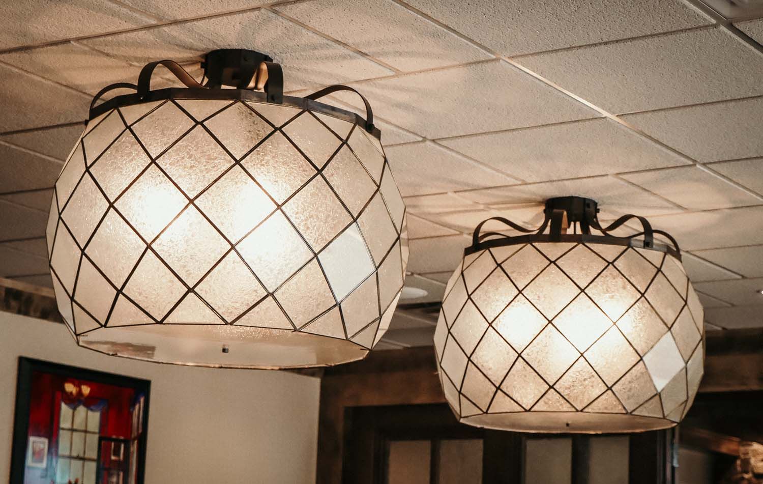 Two spherical pendant lights with diamond patterns hang from a white ceiling.