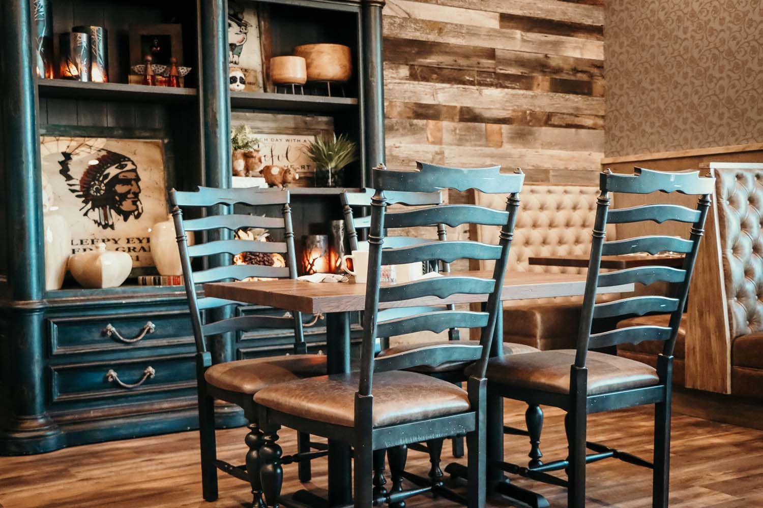Restaurant dining area with wooden table, chairs, bookcase, and a bench.