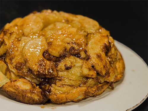 Apple upside-down cake, caramelized, served on a white plate against a dark background.