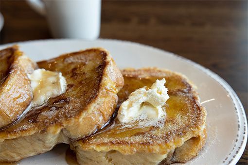 French toast with butter and syrup on a white plate.