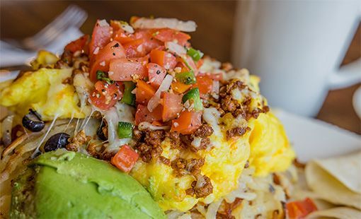 Breakfast dish with eggs, avocado, salsa, and cheese.