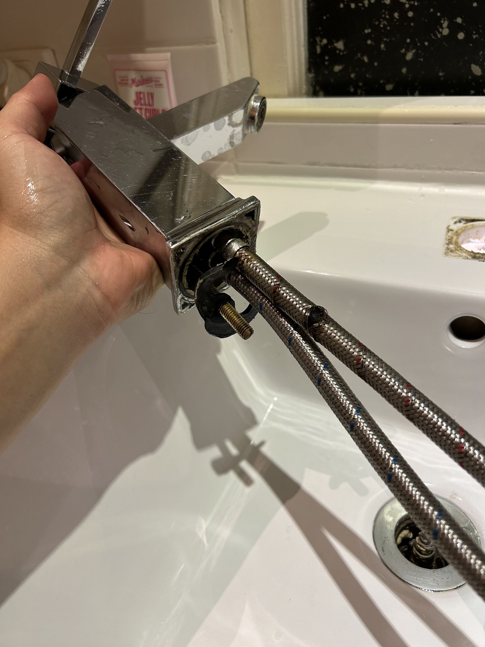 Person Using a Wrench to Tighten a Flexible Hose Connected to a Toilet Tank in a Bathroom — No.2 Plumbing In Kenmore, QLD