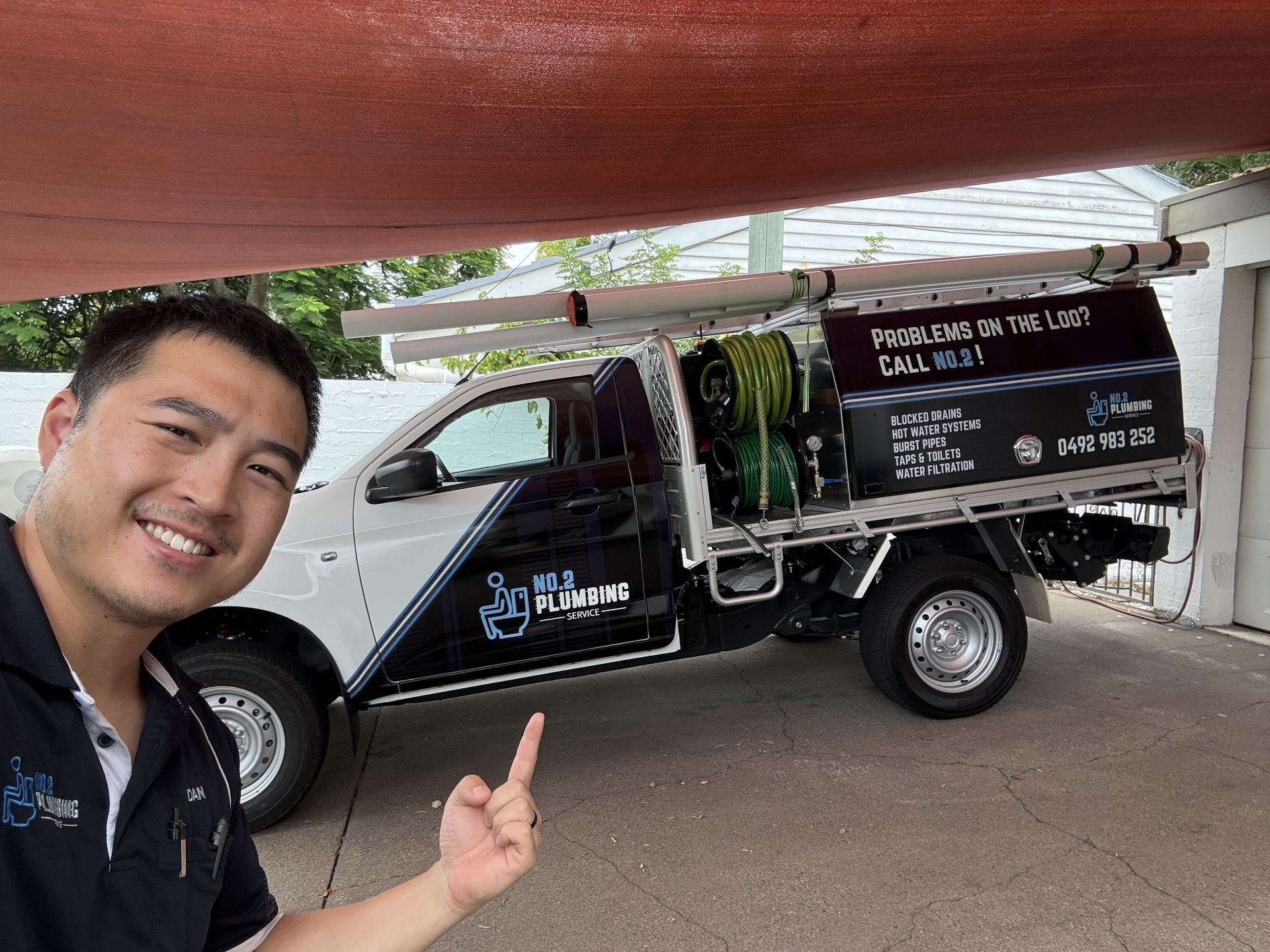 A smiling person points to a white and black work truck labeled
