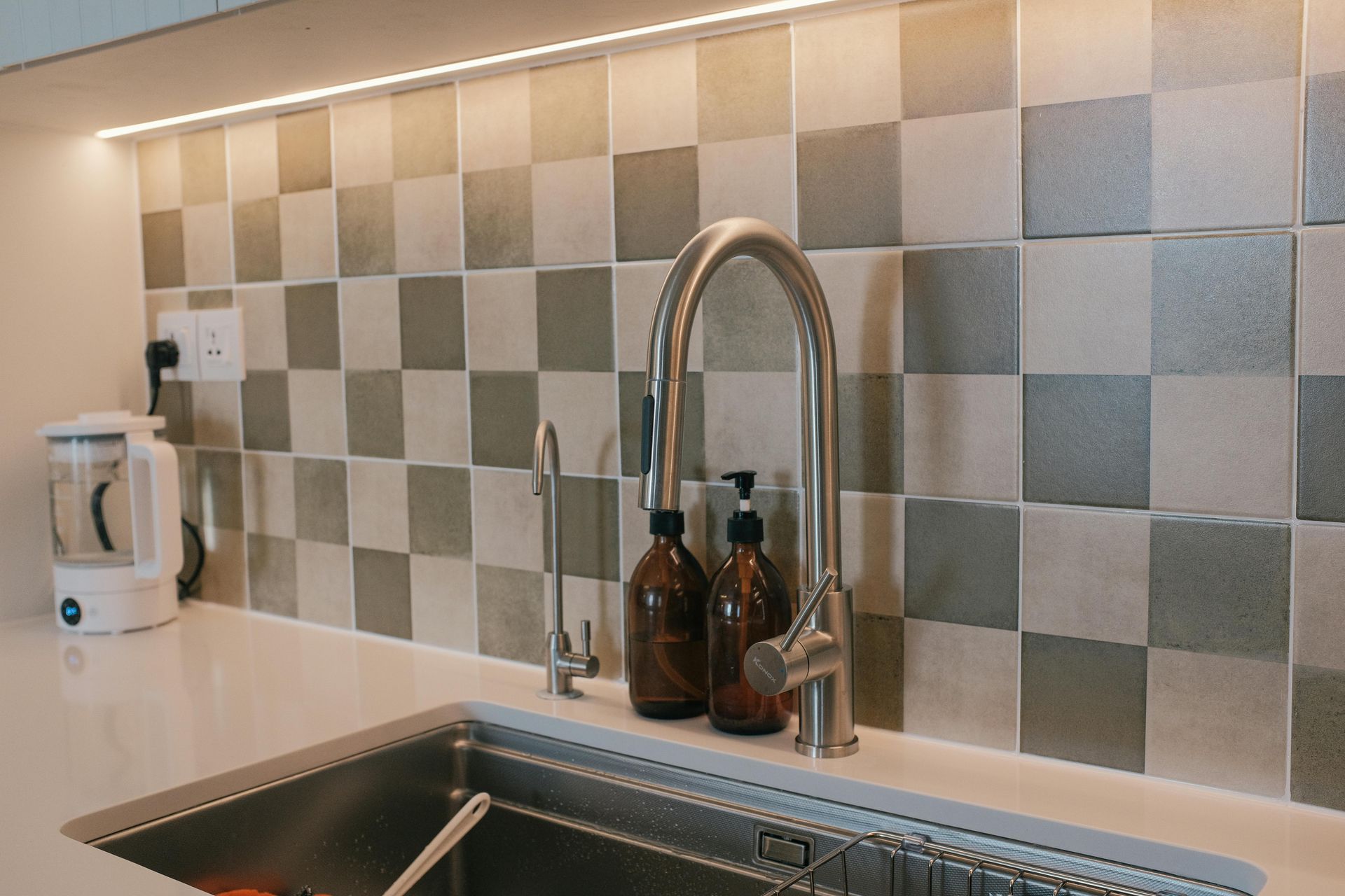 A Person Uses Pliers and a Wrench to Repair Plumbing Under a White Sink on a Tiled Floor — No.2 Plumbing In Kenmore, QLD