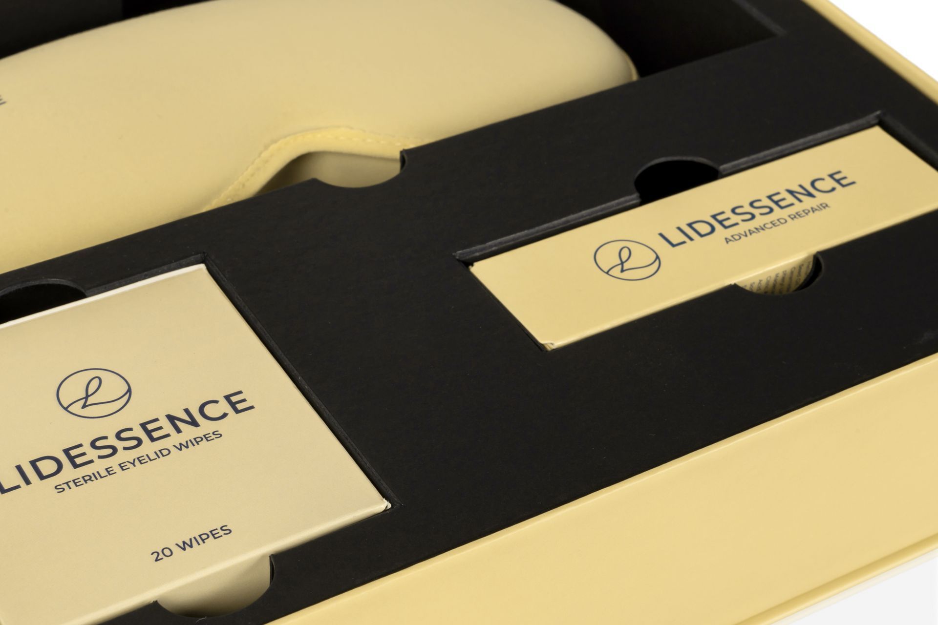Goldene und schwarze Lipdesence-Verpackungsboxen auf einer beigefarbenen Oberfläche.