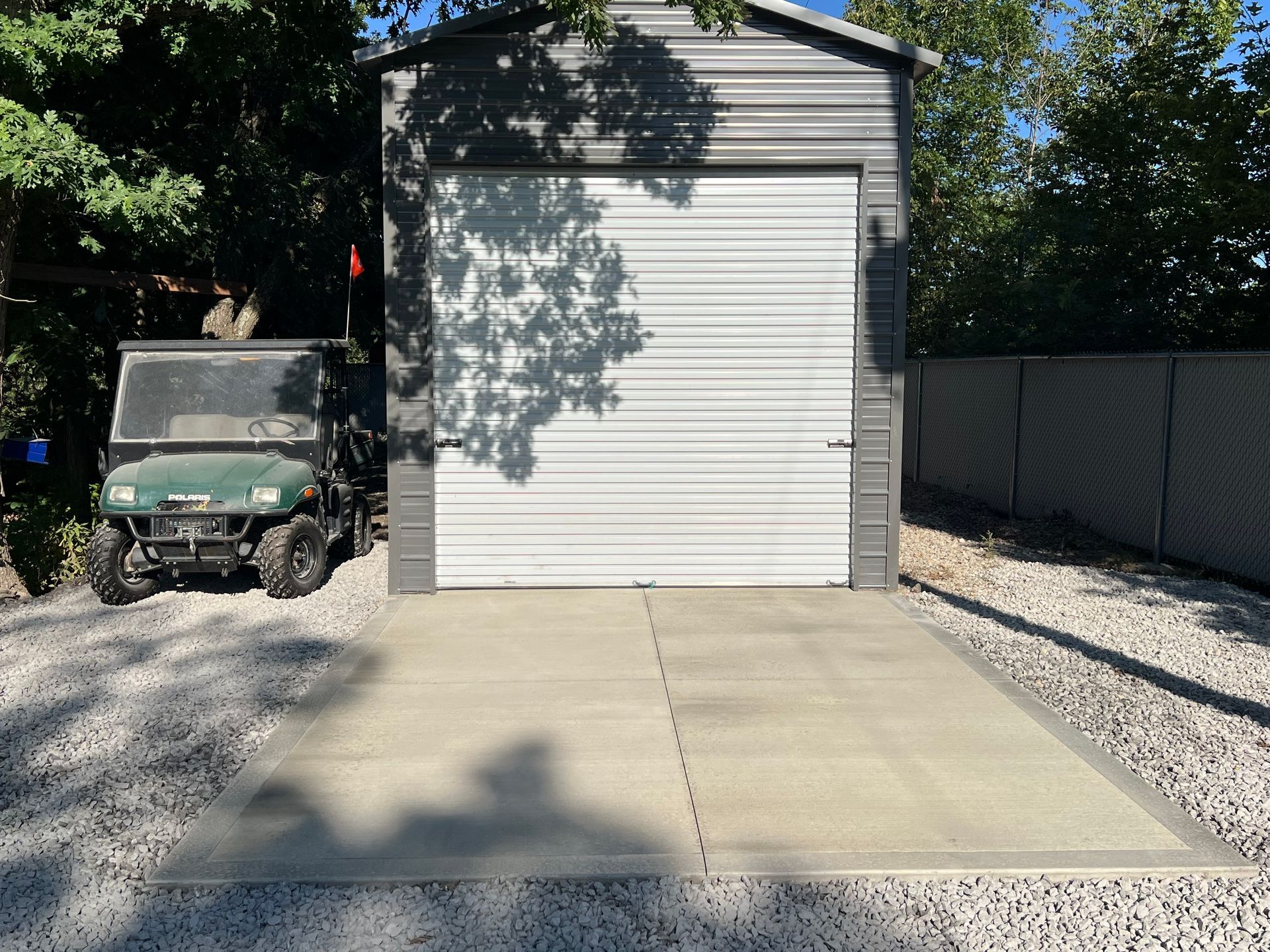 Driveway leading to a white garage, with a parked utility vehicle on the left and gravel on the right.