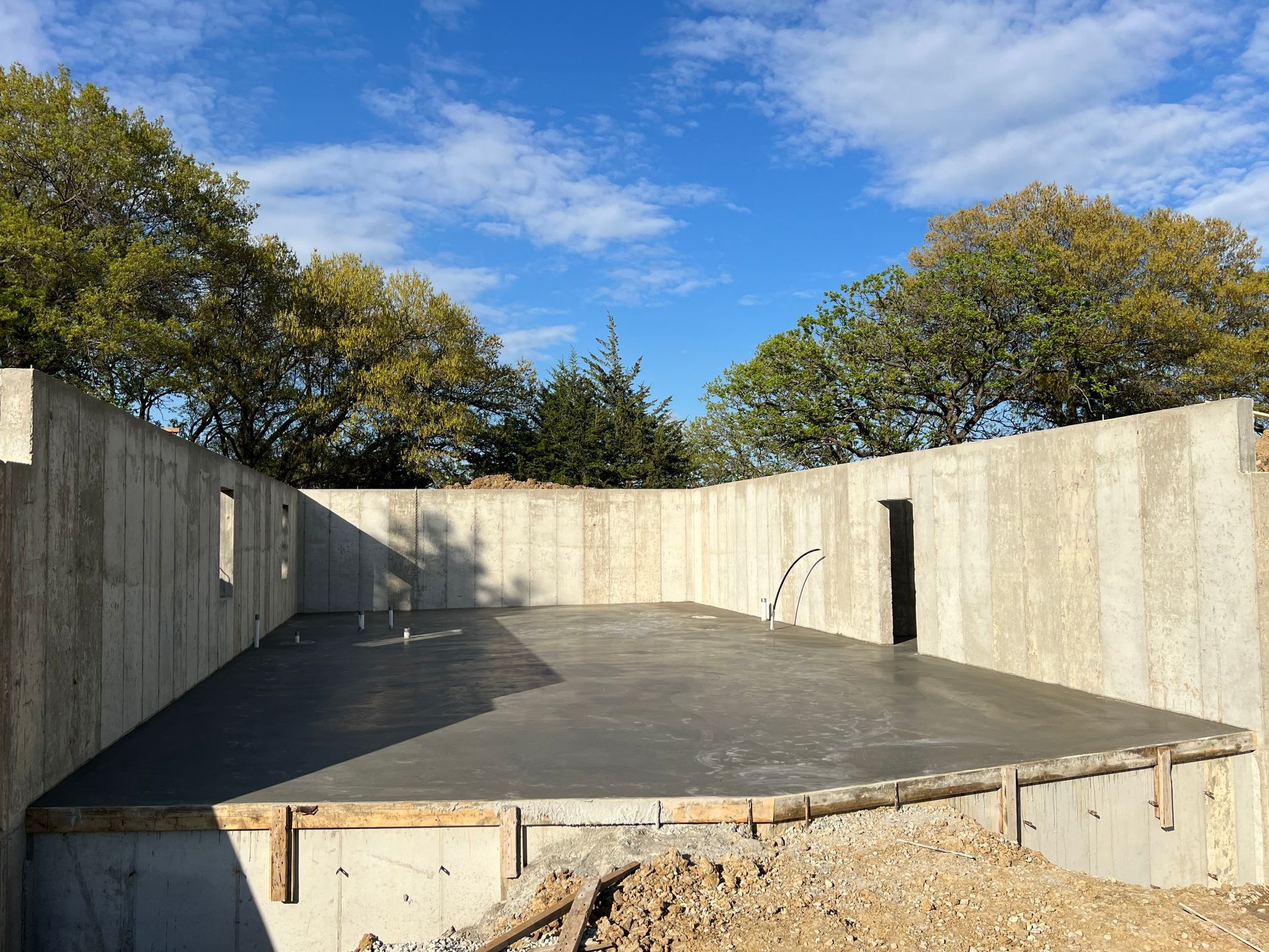 Empty concrete foundation with low walls and a blue sky above.