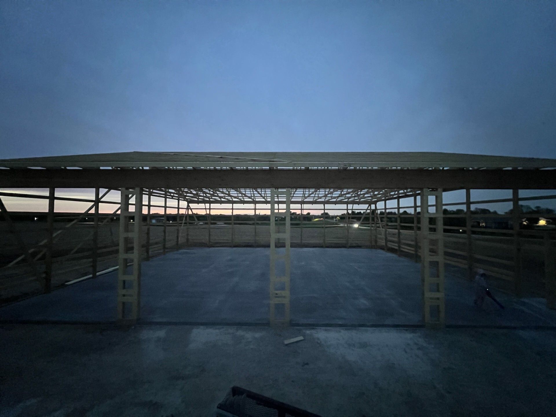 Covered parking lot under a cloudy evening sky, with empty metal carports and concrete pavement
