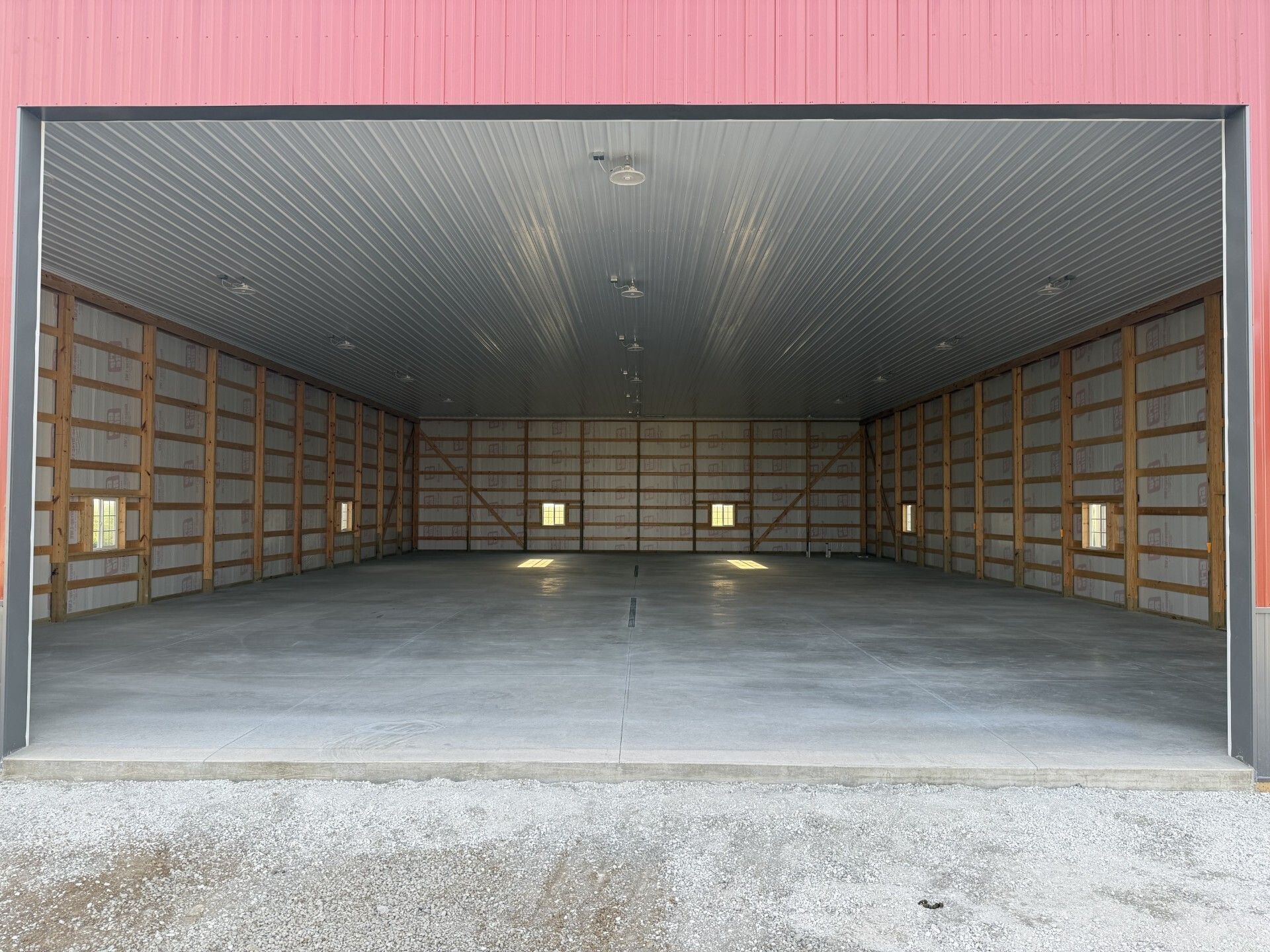 Empty unfinished garage interior with exposed wooden framing and a concrete floor