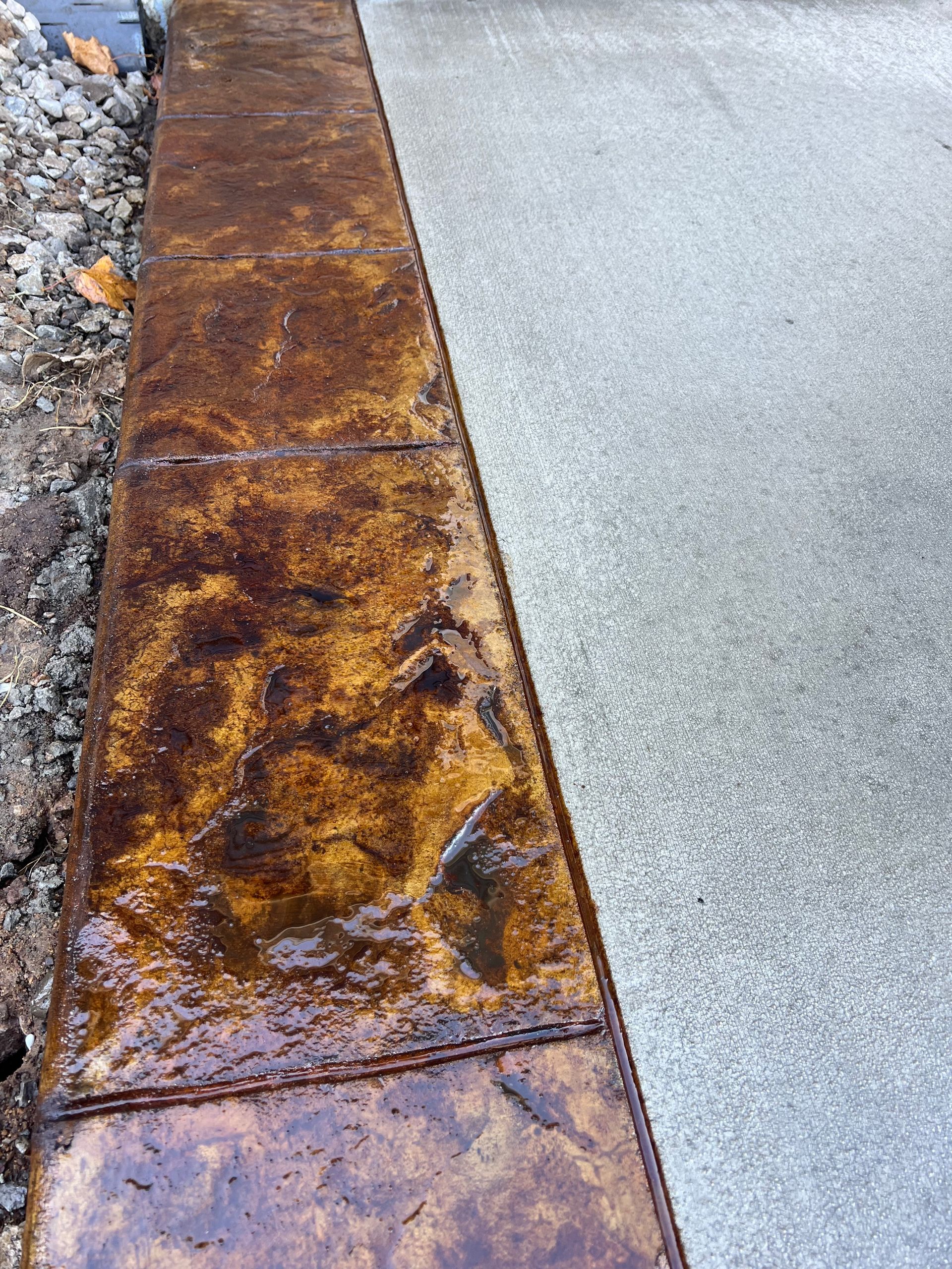 Rusty metal curb edge beside a light gray sidewalk and gravel