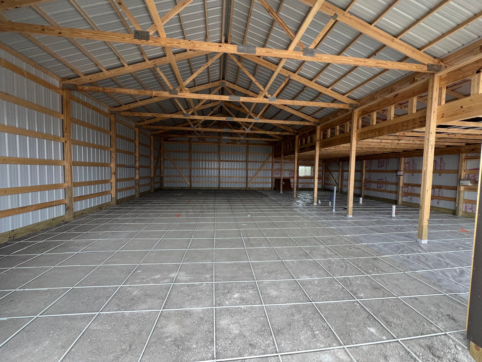 Empty metal-and-wood barn interior with concrete floor and open storage shelves