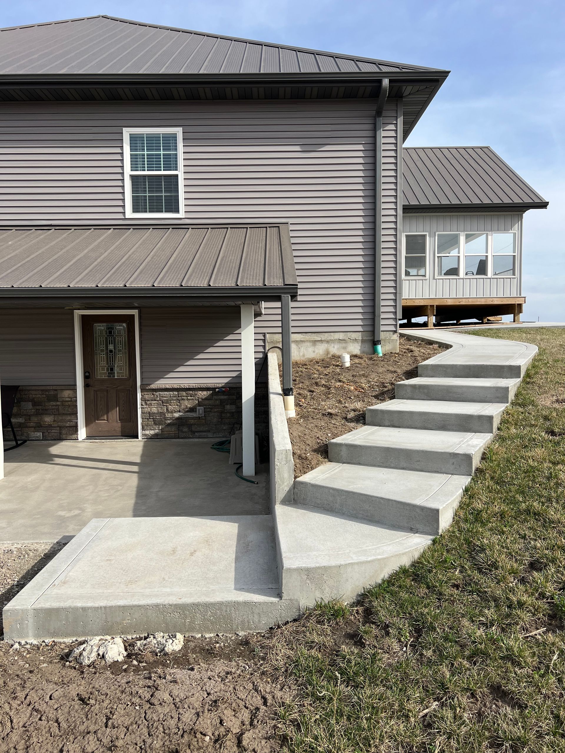 House exterior with concrete steps and sloped walkway leading to a porch and side entrance