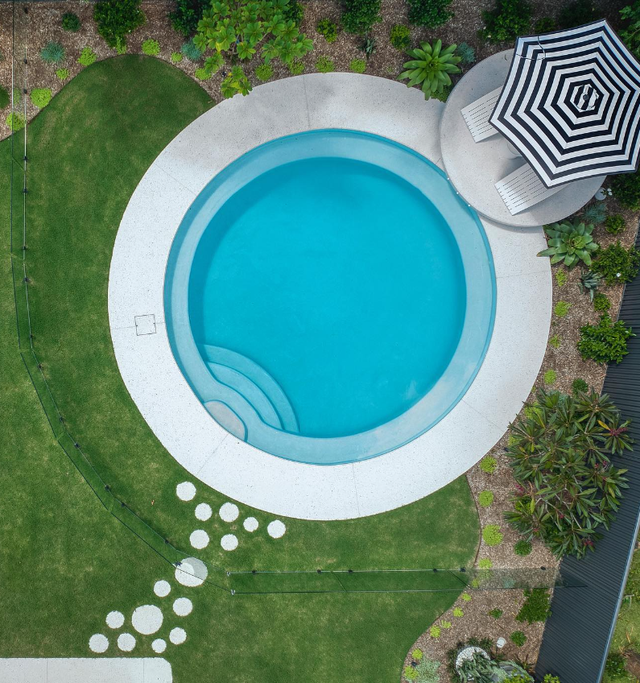 An aerial view of a swimming pool with chairs and an umbrella