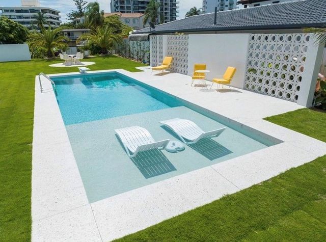 A large swimming pool with two lounge chairs in it