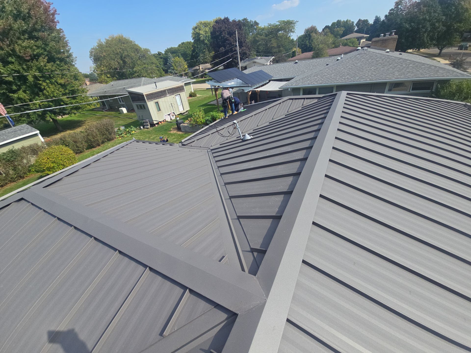Gray asphalt shingle roof on a light-colored house, with a skylight and a chimney.