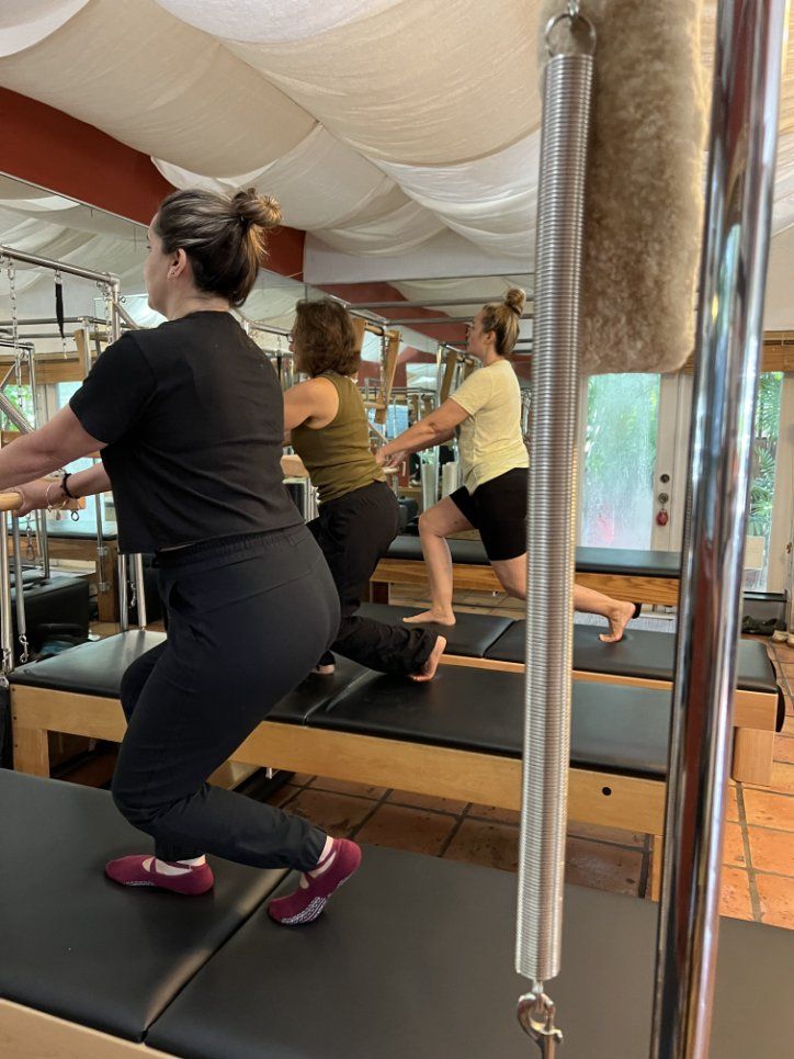 A group of women are doing exercises on a pilates machine in a studio.