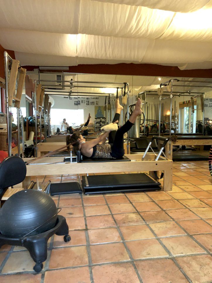 A woman is laying on a pilates machine in a gym.