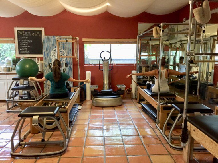 A woman is sitting on a pilates machine in a gym