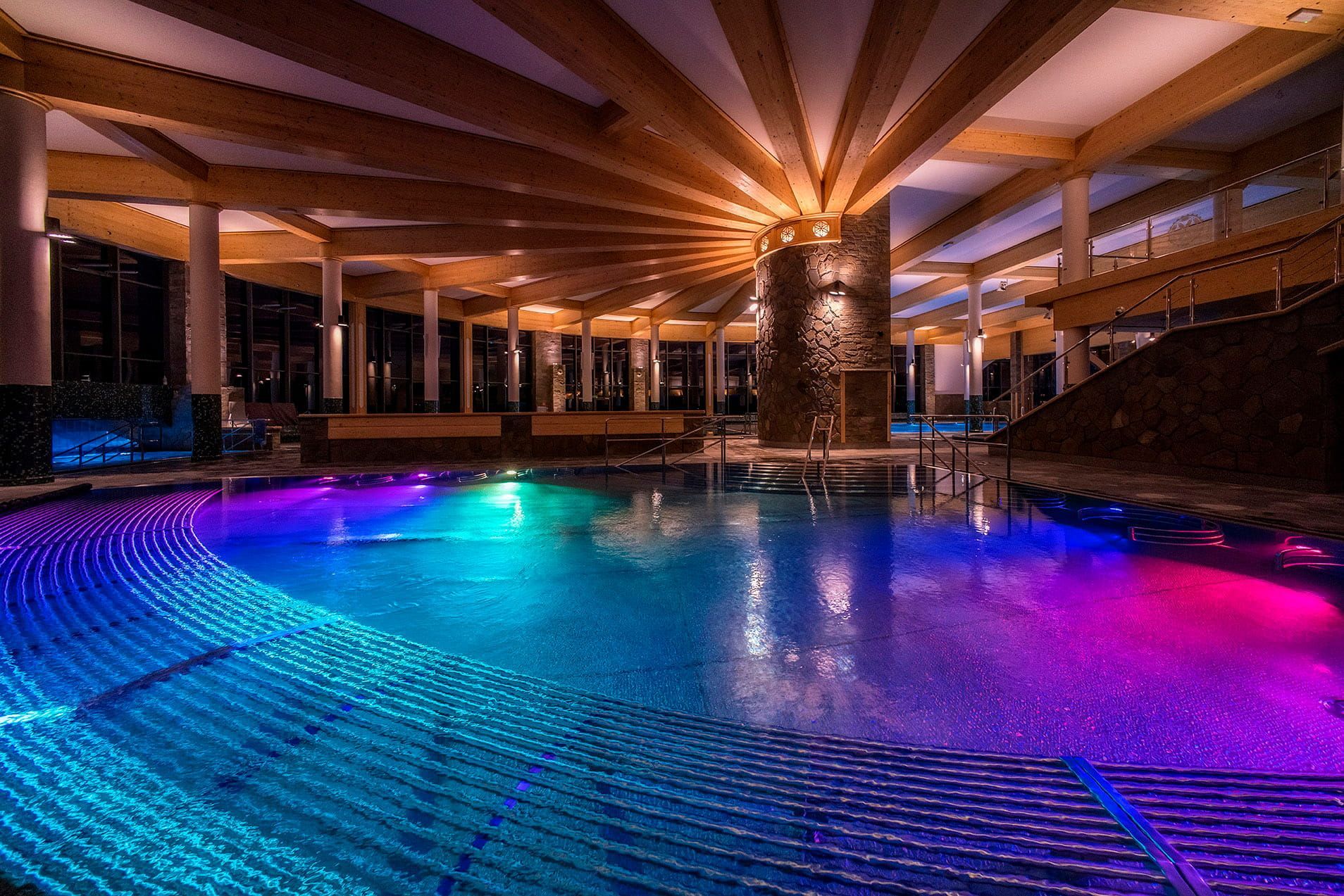 Indoor thermal pool hall at Chochołowskie Termy with a wooden roof and colourful lighting