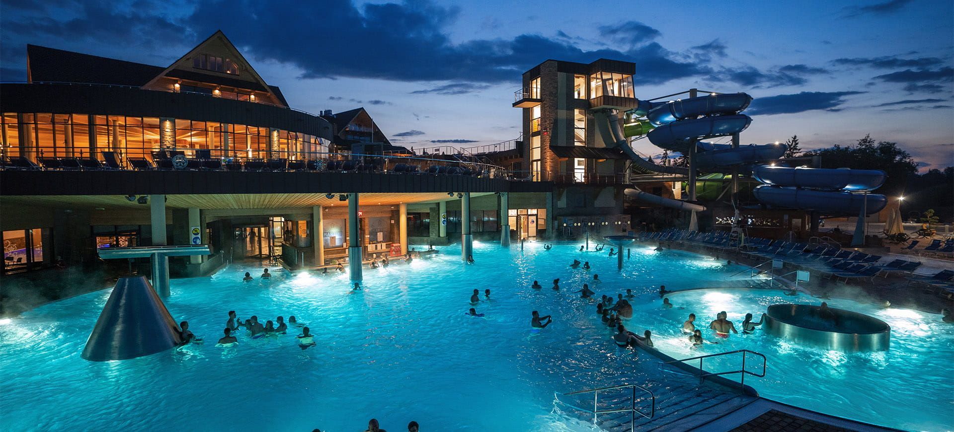 Chochołowskie Termy at night: illuminated outdoor thermal pools with the slide tower behind