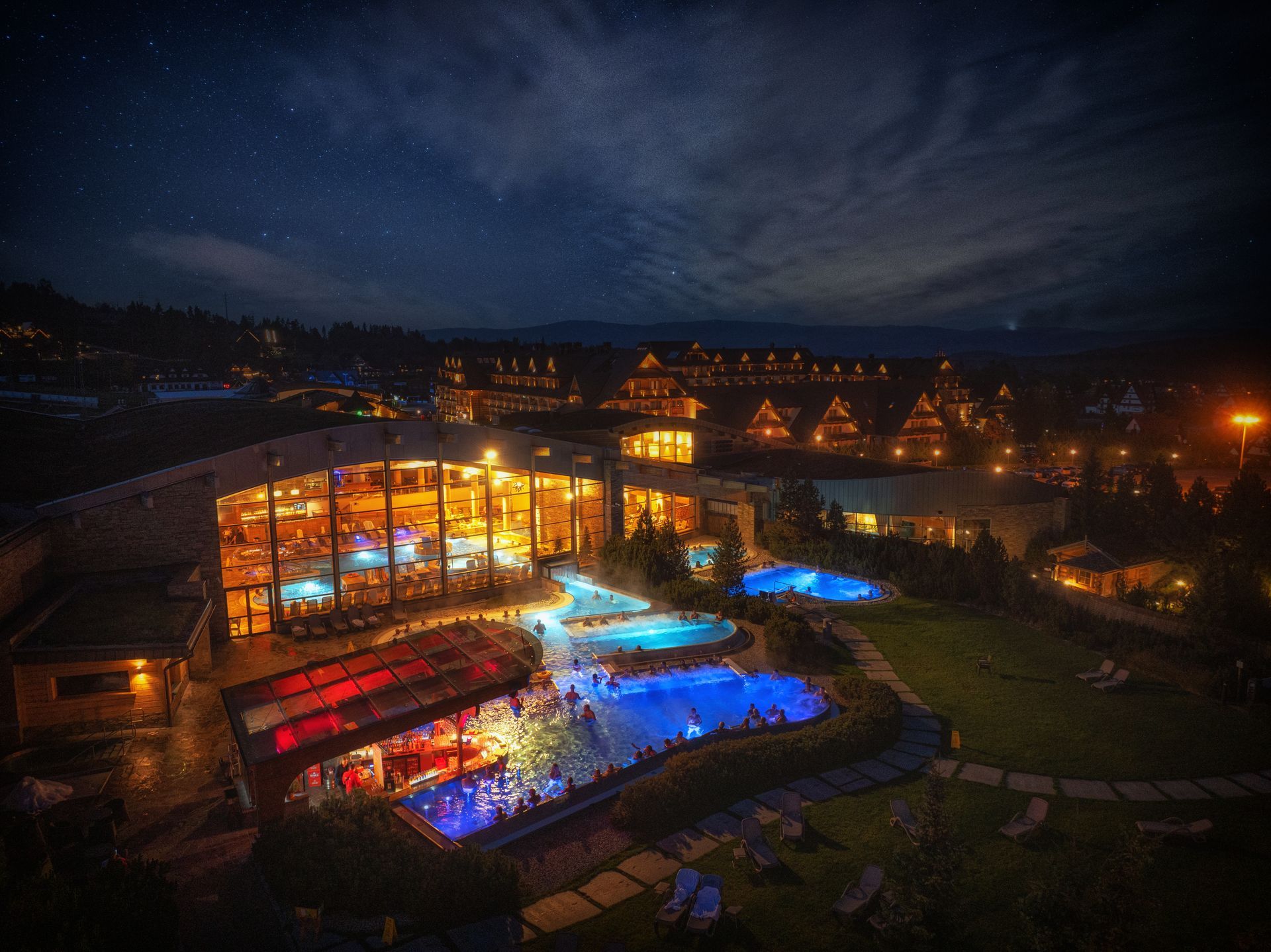 Terma Bania at night: aerial view of the illuminated thermal pool hall and outdoor pools in Białka Tatrzańska