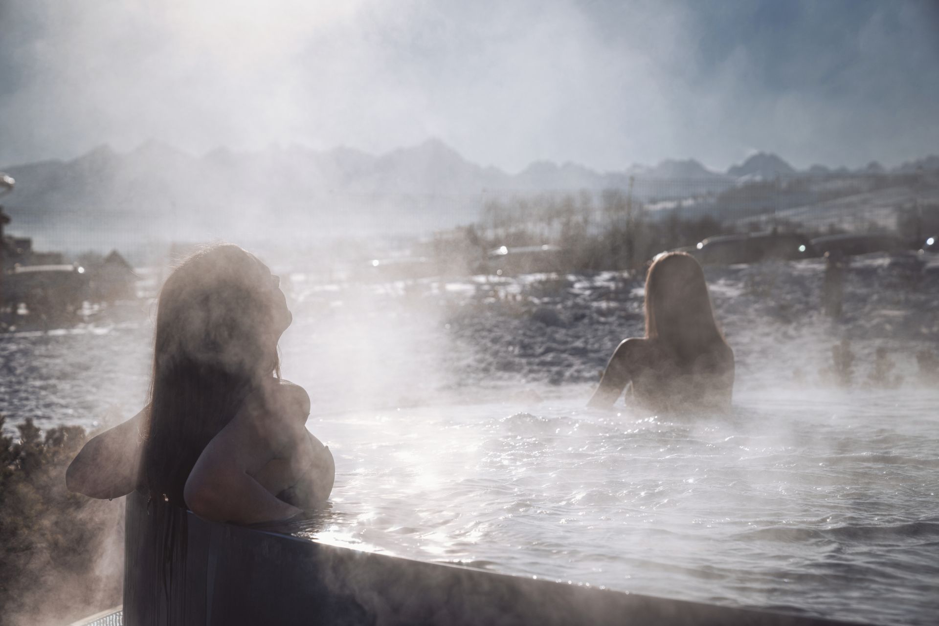 Guests relaxing in a steaming outdoor thermal pool on a winter day at Terma Bania