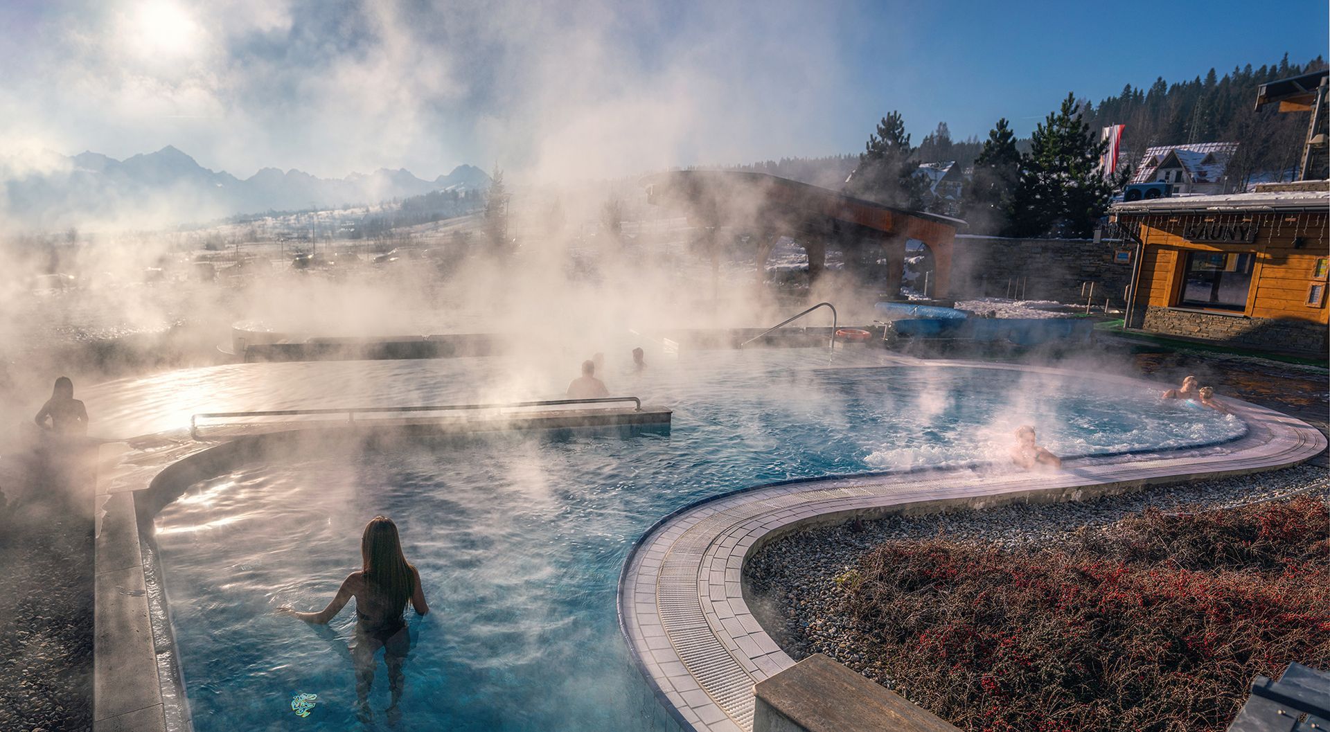 Steaming outdoor thermal pool with Tatra peaks in the background at Bania Thermal Baths
