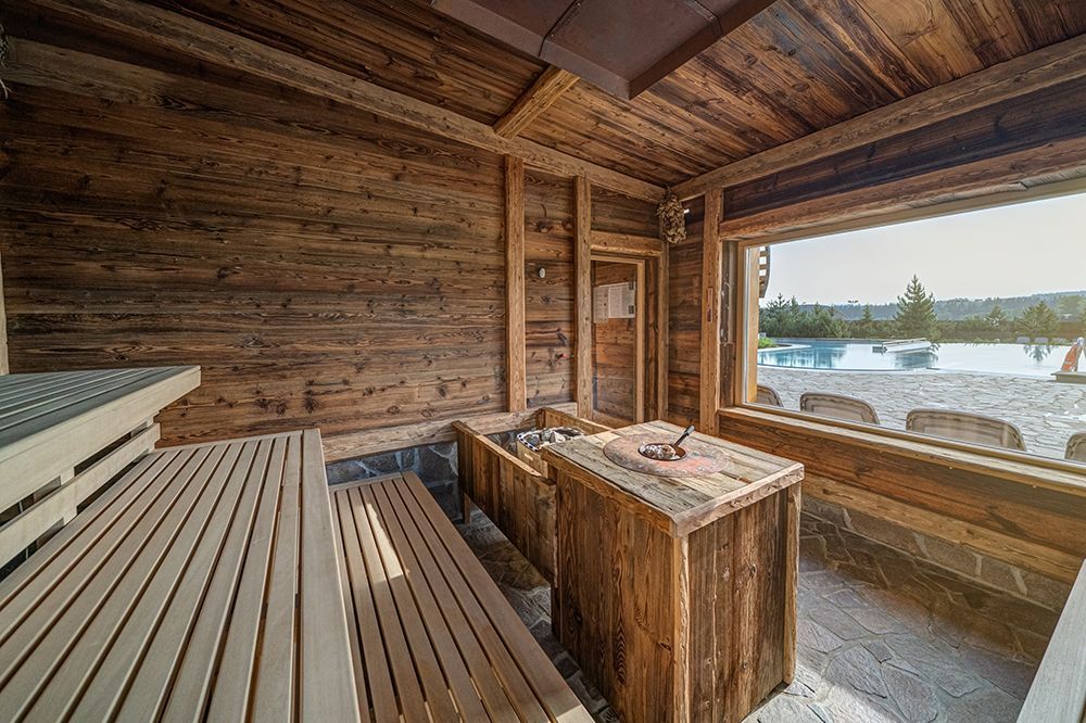Wooden sauna with a mountain-view window at Terma Bania