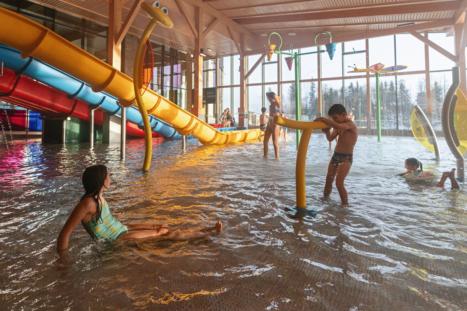 Shallow kids' play pool with water sprays and colourful slides at Chocholow Thermal Baths