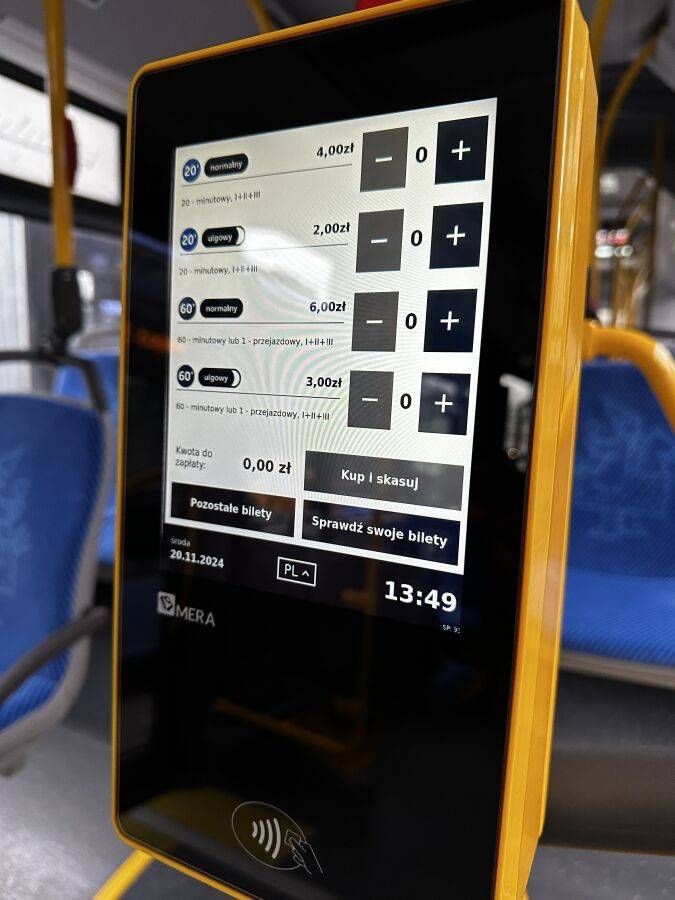 Touchscreen ticket machine on board a Kraków tram showing ticket options and a contactless payment reader