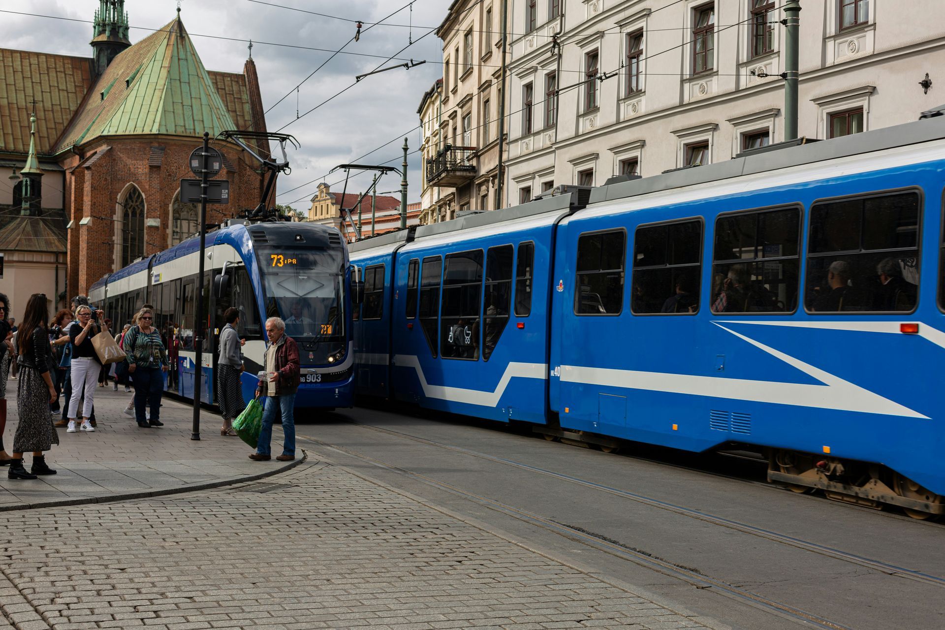 Modern blue Kraków tram stopped near the Old Town with passengers boarding