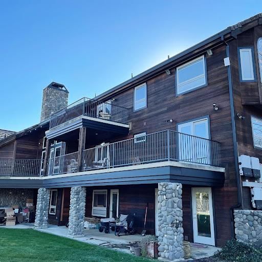 Wooden lodge exterior with balconies, stone pillars, and a chimney under a clear blue sky